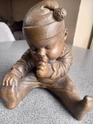 bébé assis de couleur bronze