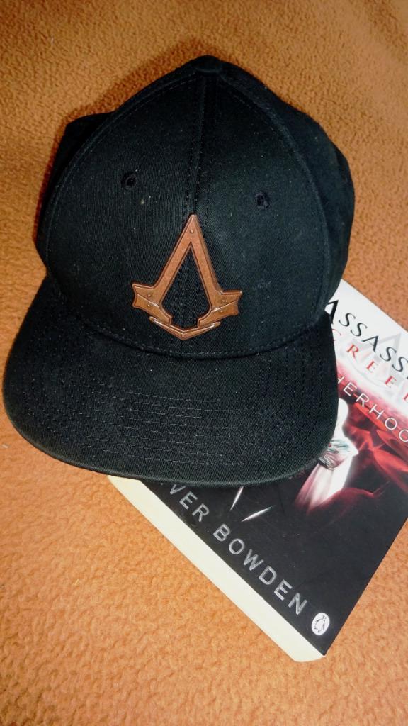 Lotje Assassins Creed Pet + Boek Brotherhood Oliver Bowden, Verzamelen, Verzenden, Nieuw, Film, Gebruiksvoorwerp