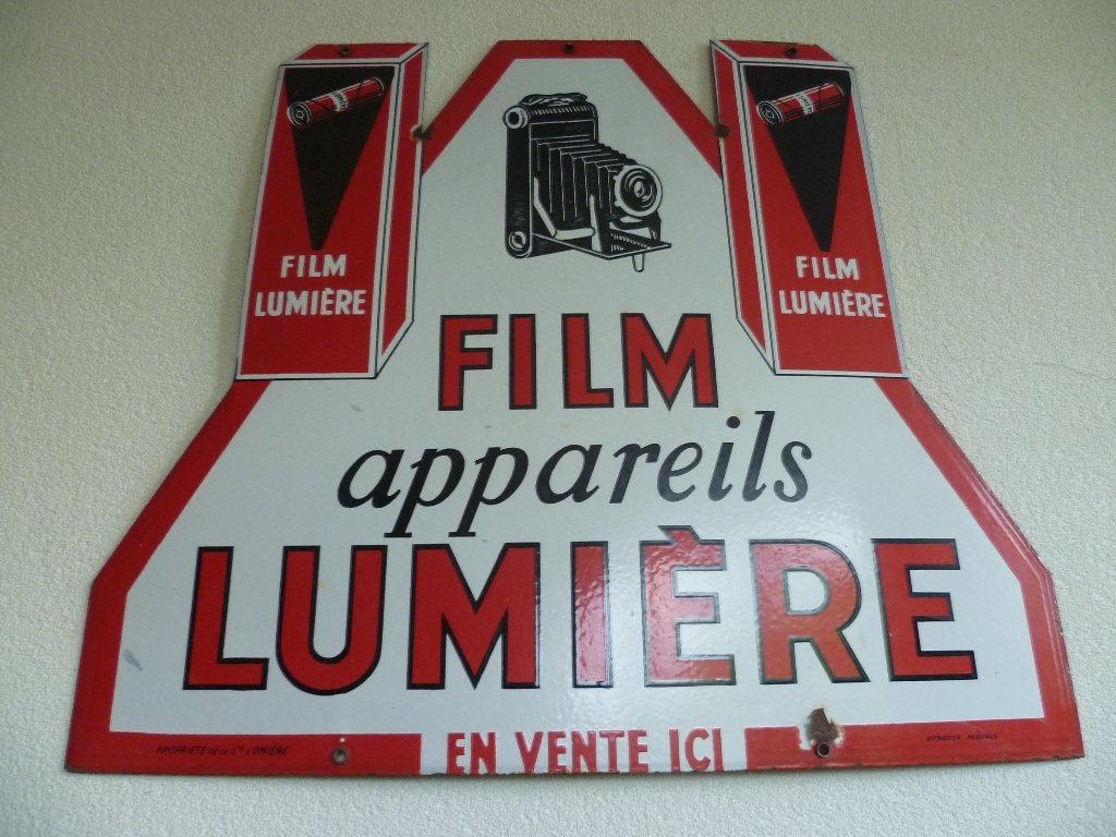 PLAQUE  ÉMAILLE« LUMIÈRE FILM EN VENTE ICI » DES ANNÉES 1930, Collections, Enlèvement ou Envoi, Utilisé, Panneau publicitaire