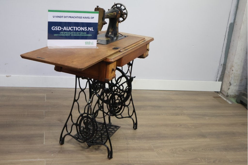 Antieke zittende naaimachine met houten tafel