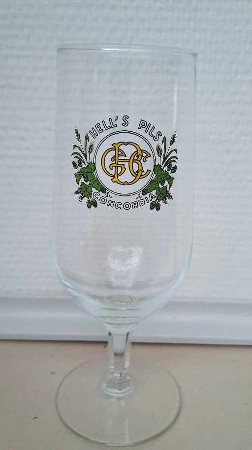 Glas op voet  Hell's Pils Concordia Geraardsbergen., Ophalen of Verzenden, Zo goed als nieuw, Bierglas