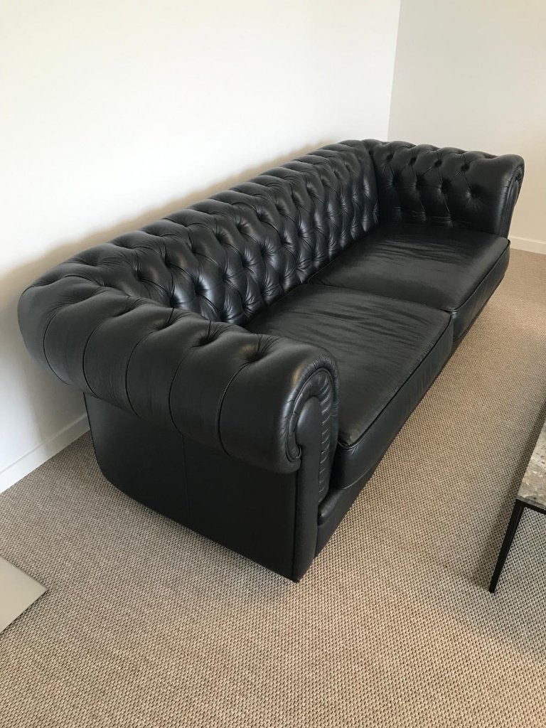 Stijlvolle zwarte Chesterfield-driezitter in leder, Ophalen, Gebruikt, Klassieke capitonnering, brede armleuningen , royale zitkussens.
