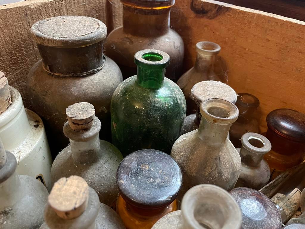 Bak vol antieke flesjes en buisjes uit laboratorium, Ophalen
