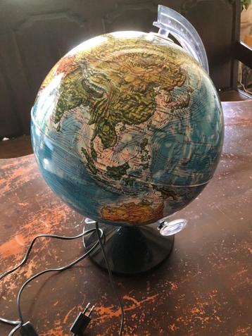 wereldbol met vergrootglas en verlichting beschikbaar voor biedingen