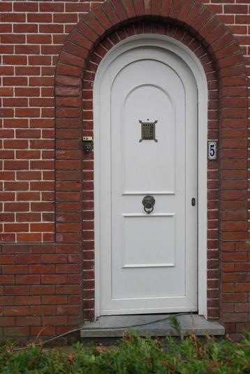 voordeur in witte PVC met kijkgat en deurklopper leeuwenkop.