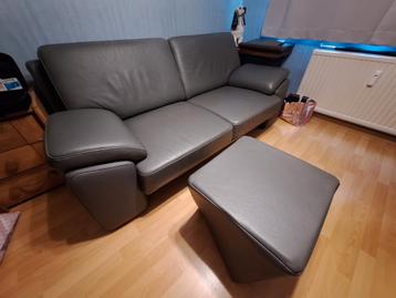 Canapé 2 places en cuir gris avec pouf disponible aux enchères