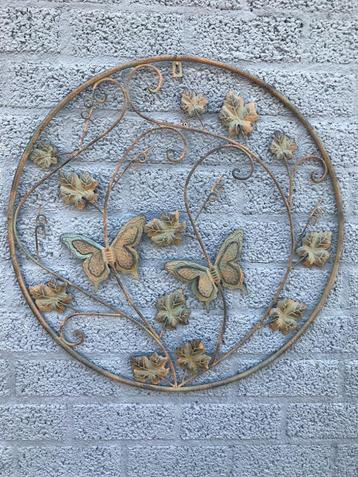 Een metalen wandornament met bladeren en vlinders, zeer deco