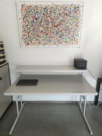 Lichtgrijs kantoorbureau met monitorplateau beschikbaar voor biedingen