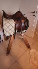 Oude turnbok met paardenzadel en houten bord met halsters, Ophalen