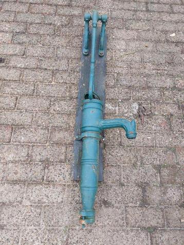 Een zeer oude   zware gietijzeren  handwaterpomp op plank beschikbaar voor biedingen