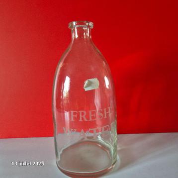 Vrij dikke glazen fles met vers water beschikbaar voor biedingen