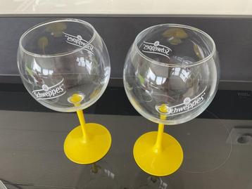 Twee glazen gin Schweppes op gele voet