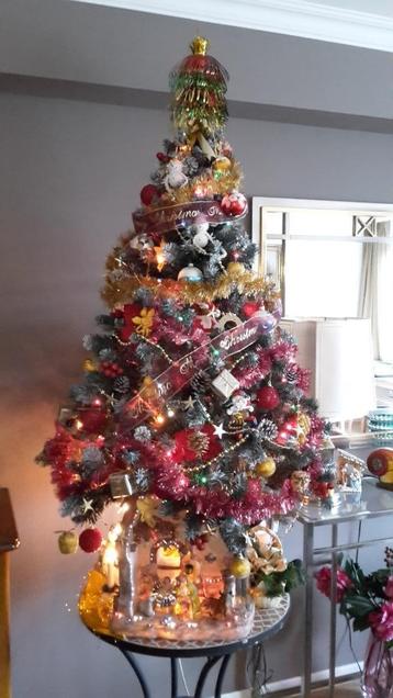 Kunstkerstboom, gegarneerd en verlichte kerststal.