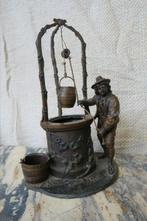 Oud bronzen beeld van een man met een waterput, Ophalen, Brons