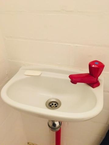 kleine witte lavabo/handenwasser met rode kraan