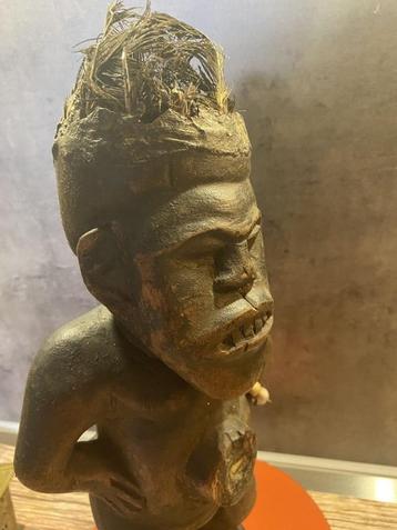 Statue d'ancêtre africain en bois ornée de plumes.