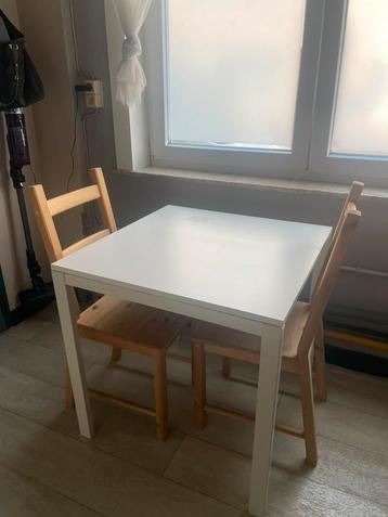 Witte tafel met houten stoeltjes beschikbaar voor biedingen