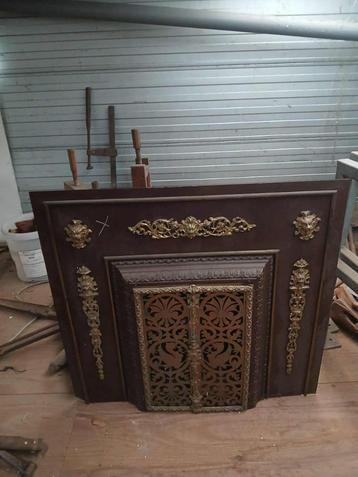 Antieke gietijzeren sierhaard met bronzen leeuwenkoppen beschikbaar voor biedingen