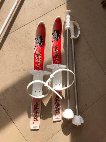 Plastic ski’s met binding over schoenen en skistokken 